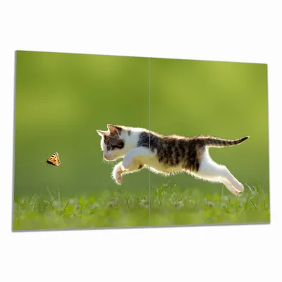 Produktbild von Wallario Herdabdeckplatte aus Glas, Größe 80 x 52 cm 2-teilig, Motiv Süße Katze fängt Schmetterling im Grünen