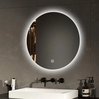 A round LED mirror is mounted on a tiled wall above a sink.
