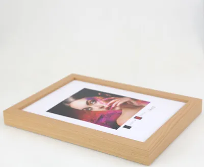 A wooden picture frame with a portrait of a woman inside, placed on a white surface.