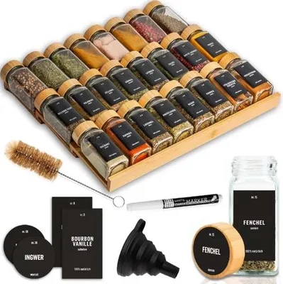 A spice rack organizer with many spice jars, labels, a brush, a funnel, and a marker.