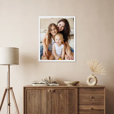 A framed picture of a mother and her two children is displayed on a wall above a wooden cabinet.