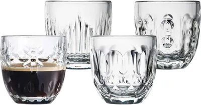 Four clear glass espresso cups are arranged on a white background. One cup in the foreground contains dark espresso.