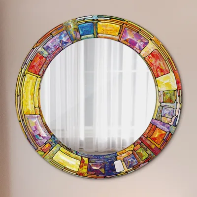 A round mirror with a colorful mosaic-style frame is displayed against a light gray wall.