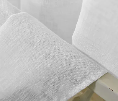 Close-up of white linen-look fabric, likely curtains, draped over a light-colored edge.
