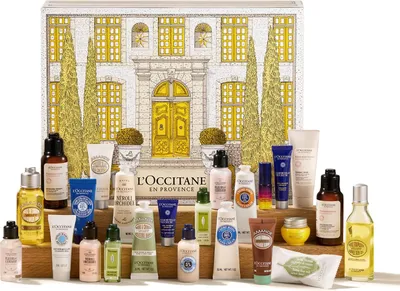 A collection of L'OCCITANE skincare and beauty products arranged in front of a decorative advent calendar designed to look like a building.