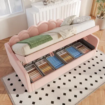 A pink upholstered bed with open storage drawers filled with neatly folded items.