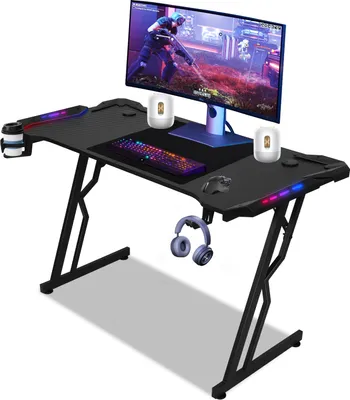 A black gaming desk with a monitor, keyboard, mouse, headphones, and cup holder.