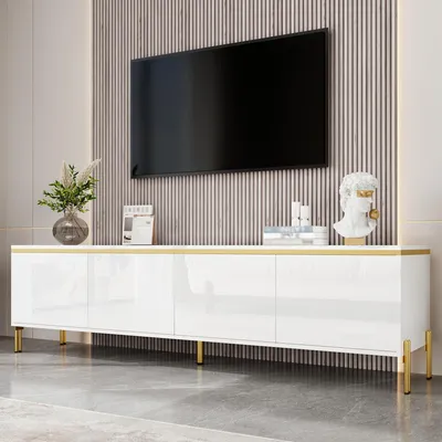 A white TV cabinet with gold accents and metal legs, with a TV mounted on a slatted wall above it.