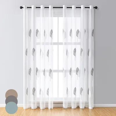 A sheer curtain with a leaf pattern hanging in front of a window.