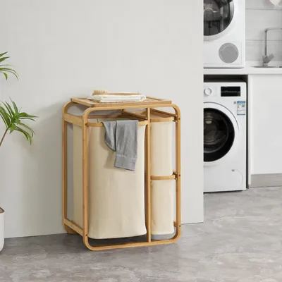 A laundry hamper with three baskets and a top shelf, placed in a laundry room next to washing machines.
