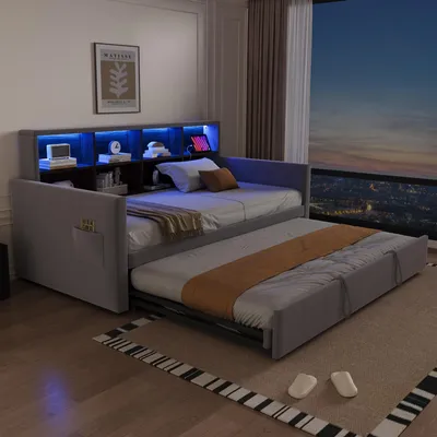 A modern daybed with a pull-out trundle bed, featuring integrated LED lighting and shelving, set in a bedroom with a large window overlooking a city at dusk.