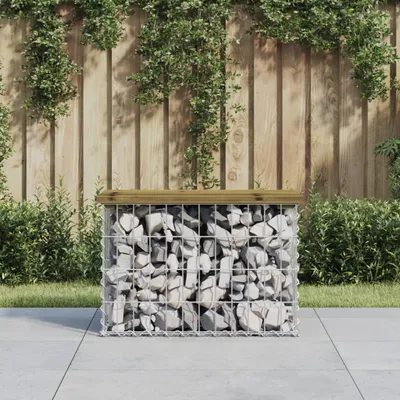 A gabion bench with a wooden top sits on a patio in front of a wooden fence with ivy growing on it.