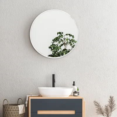 A modern bathroom vanity with a round mirror above it.