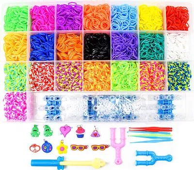 A top-down view of a craft kit containing many small colorful rubber bands, loom tools, and charms, neatly organized in a plastic case.