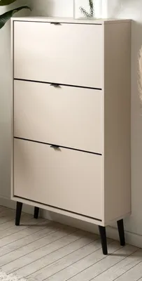 A beige shoe cabinet with three flip-down doors and black legs, standing on a light wooden floor.