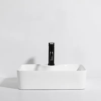 A white ceramic sink with a black faucet against a white background.