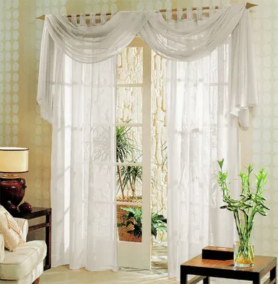 A living room scene with a large window covered by sheer white curtains and a decorative valance.