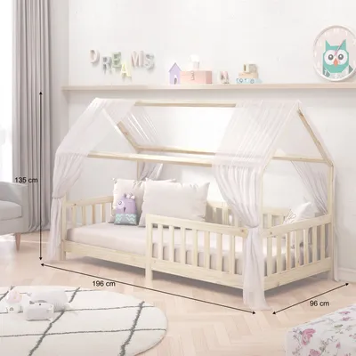 A child's bedroom with a wooden house bed, decorated with a canopy and pillows. The room also features shelves with decorative items and a rug on the floor.