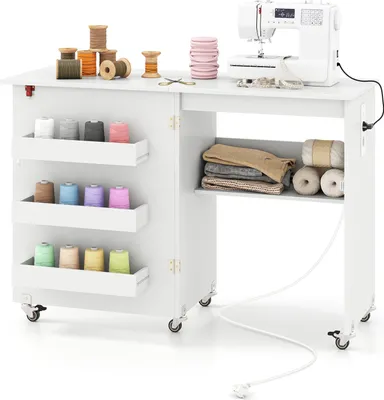 A white sewing table with a sewing machine on top and various spools of thread and fabric stored in shelves.