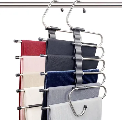 A multi-tiered hanger for pants is shown hanging on a clothing rack against a white background.