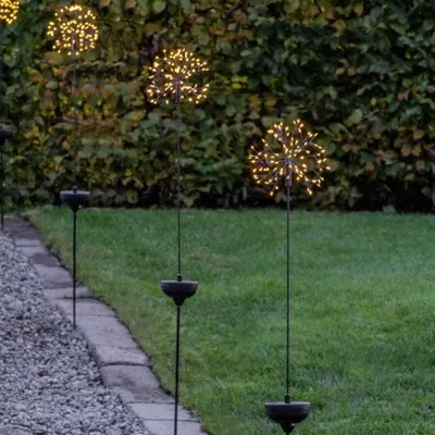 Garden path with solar-powered LED firework lights at dusk.