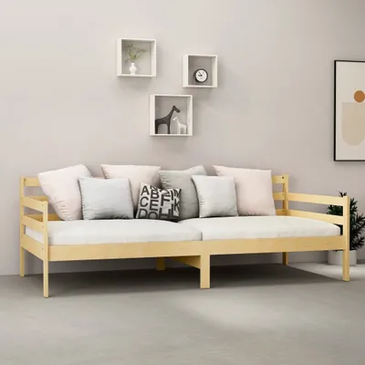 A light wood daybed with several pillows is shown against a light gray wall with three square shelves above it.