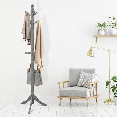 A gray wooden coat rack with items hanging on it, placed in a room with a chair and a lamp.