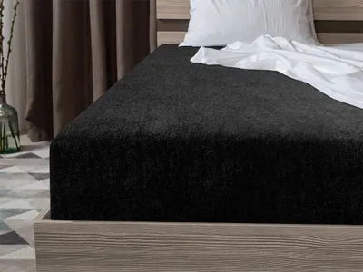 A close-up view of a black fitted sheet on a bed.