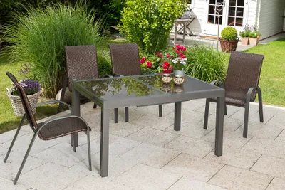 An outdoor patio set with a table and chairs on a paved patio, surrounded by greenery.