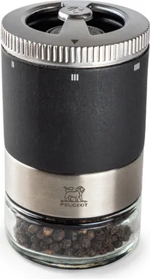 A close-up studio shot of a PEUGEOT pepper mill filled with peppercorns.