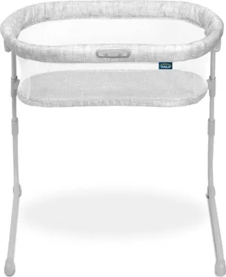 A white baby bassinet with a gray patterned fabric trim and a gray mattress.