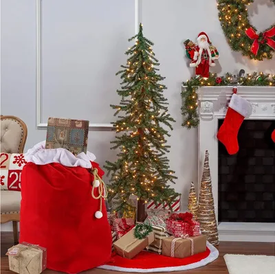A Christmas scene with a decorated tree, presents, stockings, and a large red Santa sack.