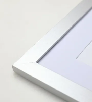 A close-up view of the corner of a silver picture frame with a white mat.