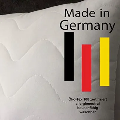 A close-up of a white quilted pillow with text and German flag colors.