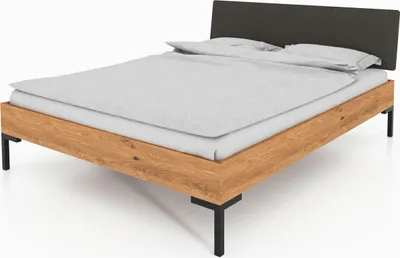 A bed with a wooden frame, upholstered headboard, and duvet.