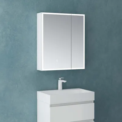 A white medicine cabinet with LED lighting is mounted on a blue textured wall above a white sink and vanity.