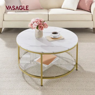 A round coffee table with a marble-like top and gold legs, placed in a living room setting with a sofa and rug.