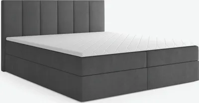 A dark gray upholstered boxspring bed with a mattress and topper, shown from a side angle against a white background.