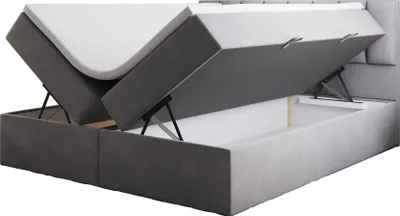 A gray upholstered boxspring bed with the mattress and storage compartments open, revealing the interior.