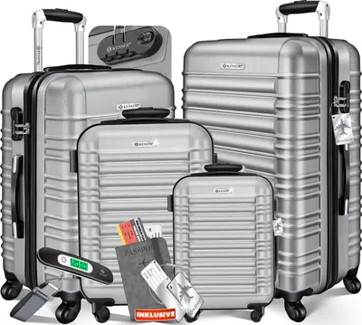 A collection of silver luggage pieces of various sizes, along with travel accessories like a scale, passport, and tickets.