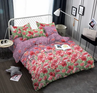 A bed with a poppy-patterned duvet set and pillows, a bedside table with a lamp and books, and decorative items on the wall.