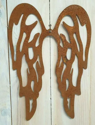 A pair of rusty metal angel wings mounted on a light-colored wooden wall.