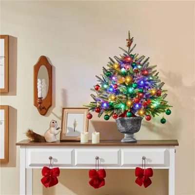 A small decorated Christmas tree on a console table.