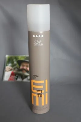 A Wella EIMI Super Set hairspray can is displayed against a gray background, with a blurred image of a person holding a fish in the background.