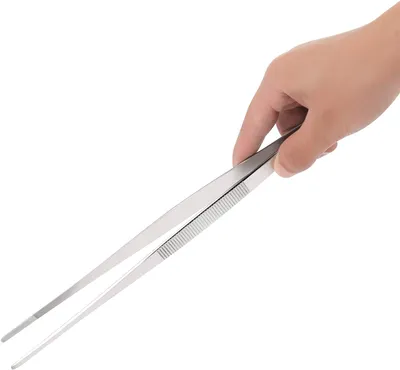 A hand holding a pair of stainless steel kitchen tongs against a white background.