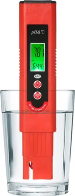 A red digital pH meter submerged in a glass of clear water.