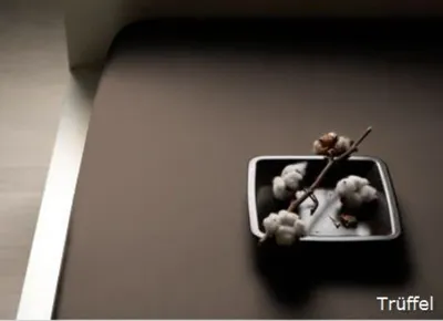 A close-up view of cotton bolls in a metal dish on a brown surface.
