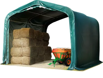 A green tarp shelter with hay bales and a farm implement inside.