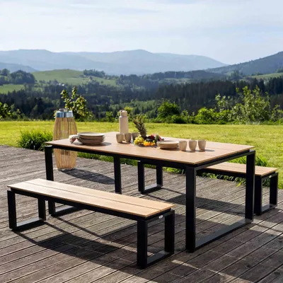 An outdoor dining set with a table and two benches on a wooden deck, with a scenic mountain landscape in the background.