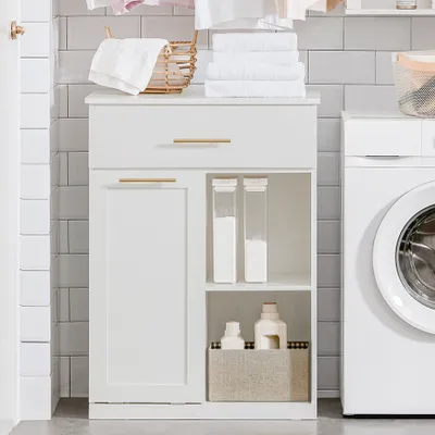 A white bathroom cabinet with a laundry basket, drawer, and shelves, placed next to a washing machine.